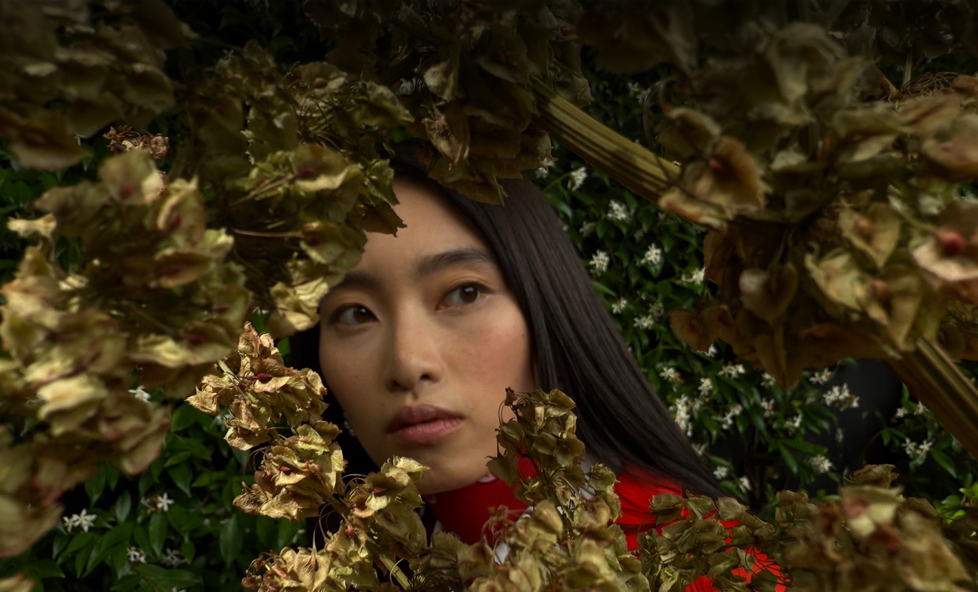 Close up photograph of a woman surrounded by foliage