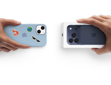 Mains échangeant des appareils dans le cadre d’une reprise. iPhone 13 dans une coque en silicone avec des stickers sur la face arrière, échange avec un coffret du nouvel iPhone 17.